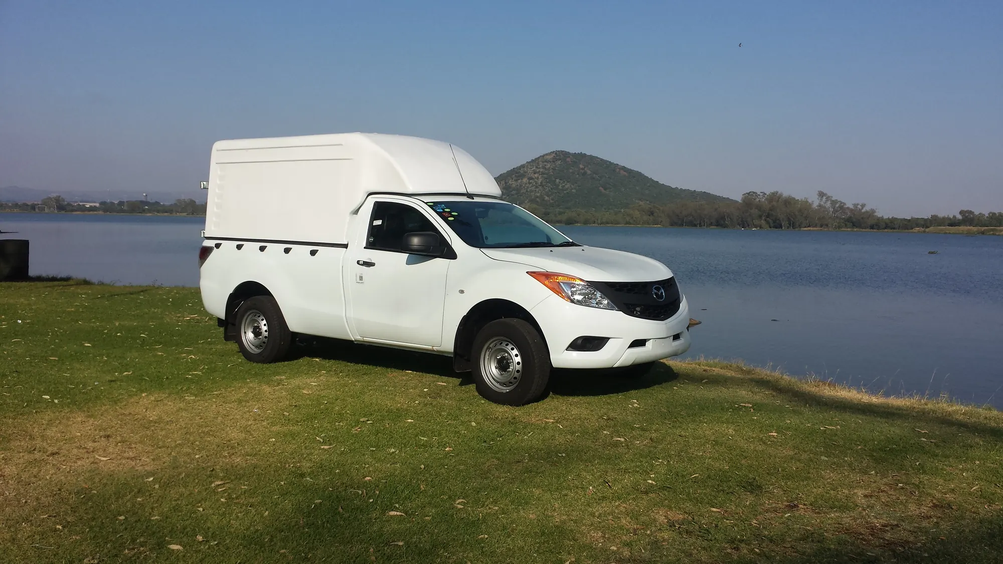 White Mazda BT-50 fitted with a Club Canopies Space Saver canopy beside the dam