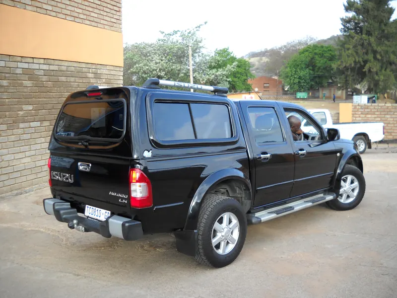 Black Isuzu KB double cab with a colour-matched canopy and aluminium roof rack.