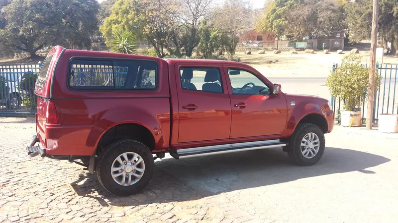 Red Tata Xenon double cab with a colour-matched canopy, side view.