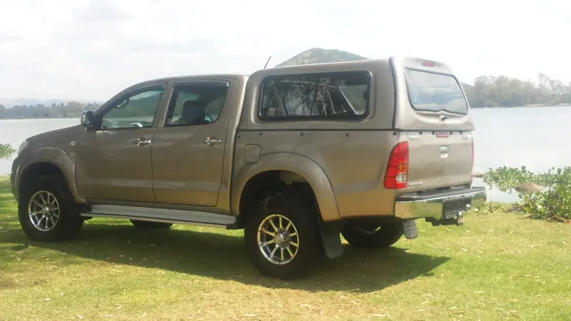 Bronze Toyota Hilux double cab with a colour-matched canopy beside the dam.