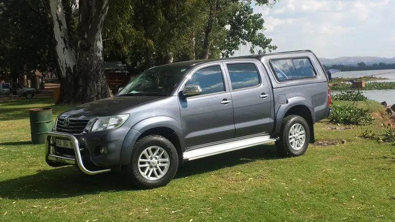 Grey Toyota Hilux double cab with canopy, front three-quarter view.