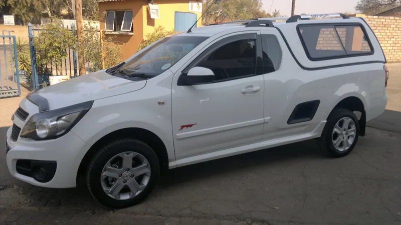 White Chevrolet Utility with a Full House canopy and roof rails.