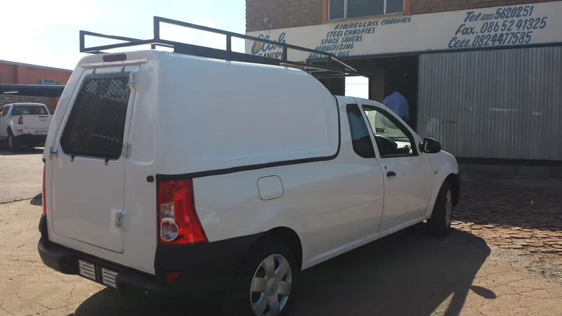 White Nissan NP200 with a Space Saver canopy and steel roof rack.