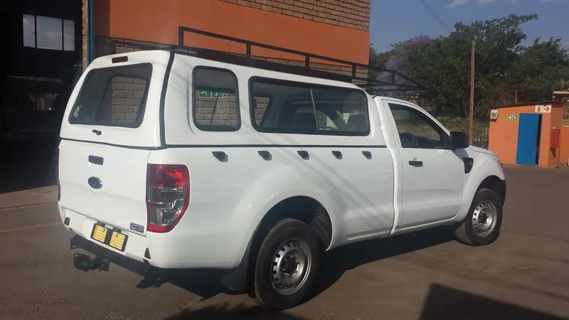 White Ford Ranger single cab with canopy and steel roof rack.