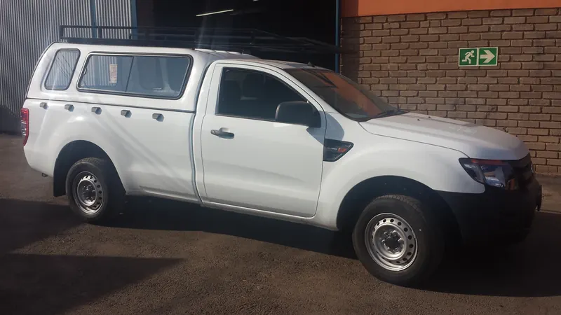 White Ford Ranger single cab with canopy and steel roof rack, front view.