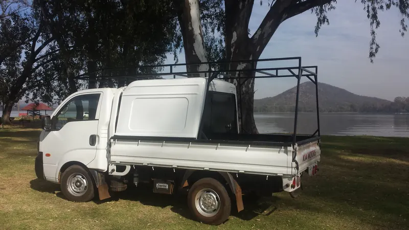Kia K2700 dropside with a half canopy and steel frame rack.