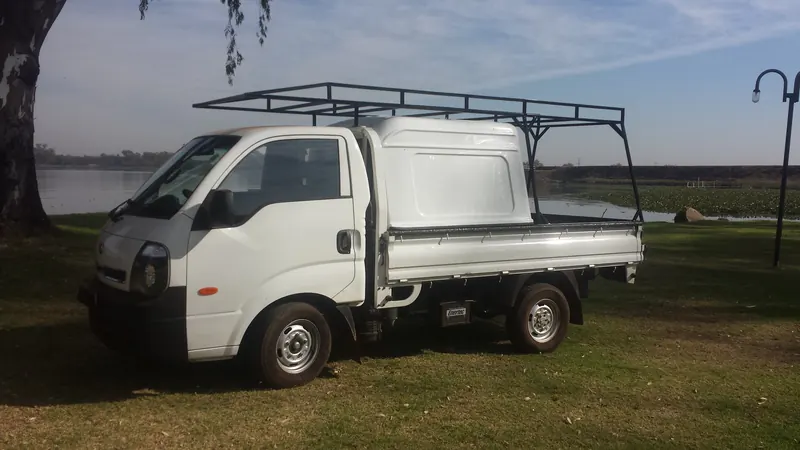Kia K2700 dropside with a half canopy and steel frame rack, front view.