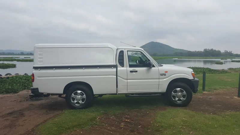 White Mahindra single cab with a canopy beside the dam.