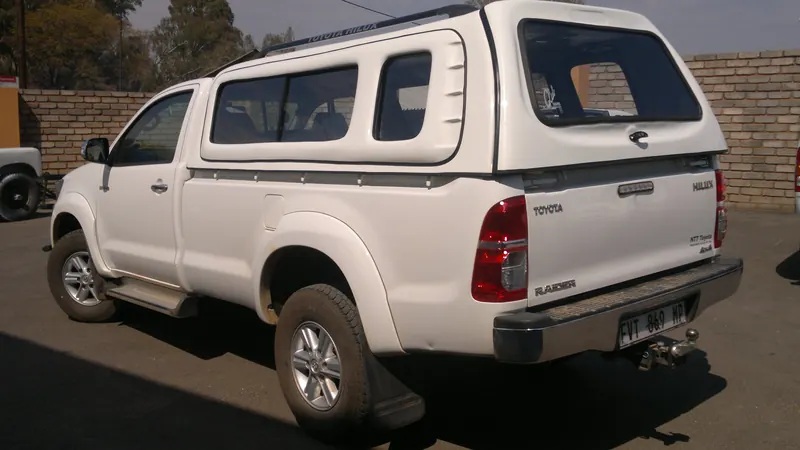 White Toyota Hilux single cab with a Full House canopy, rear view.