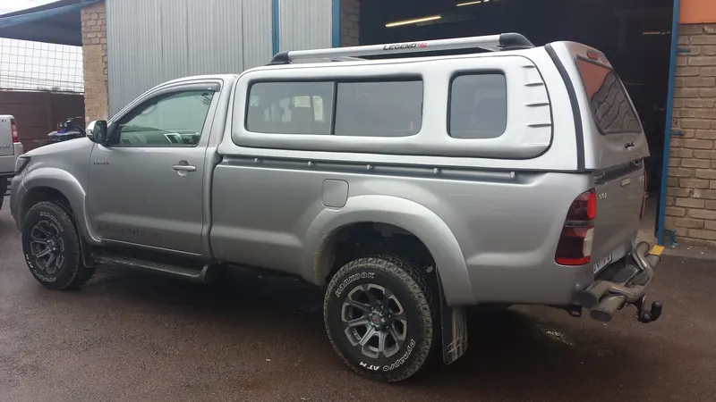 Silver Toyota Hilux single cab with a colour-matched canopy and roof rails.