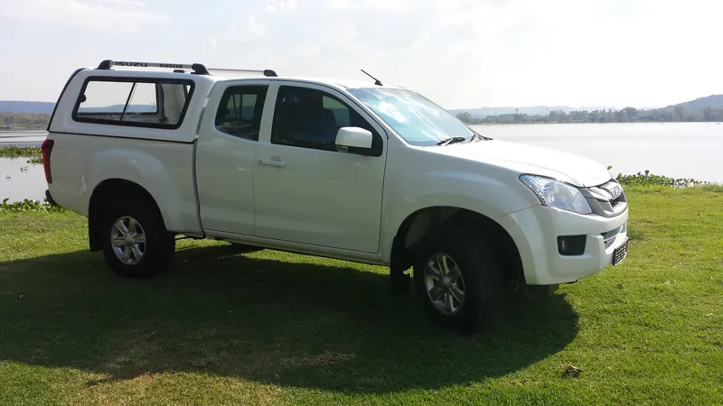 White Isuzu KB Extended Cab with a Full House canopy and roof rack beside the dam.