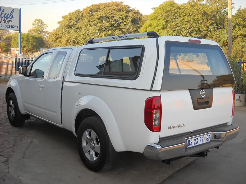 White Nissan Navara King Cab with canopy and roof rack.