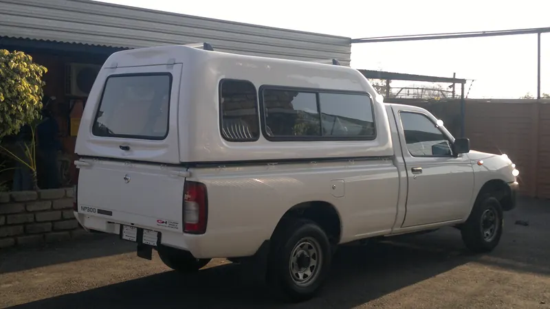 White Nissan NP300 Hardbody with a high-roof canopy.